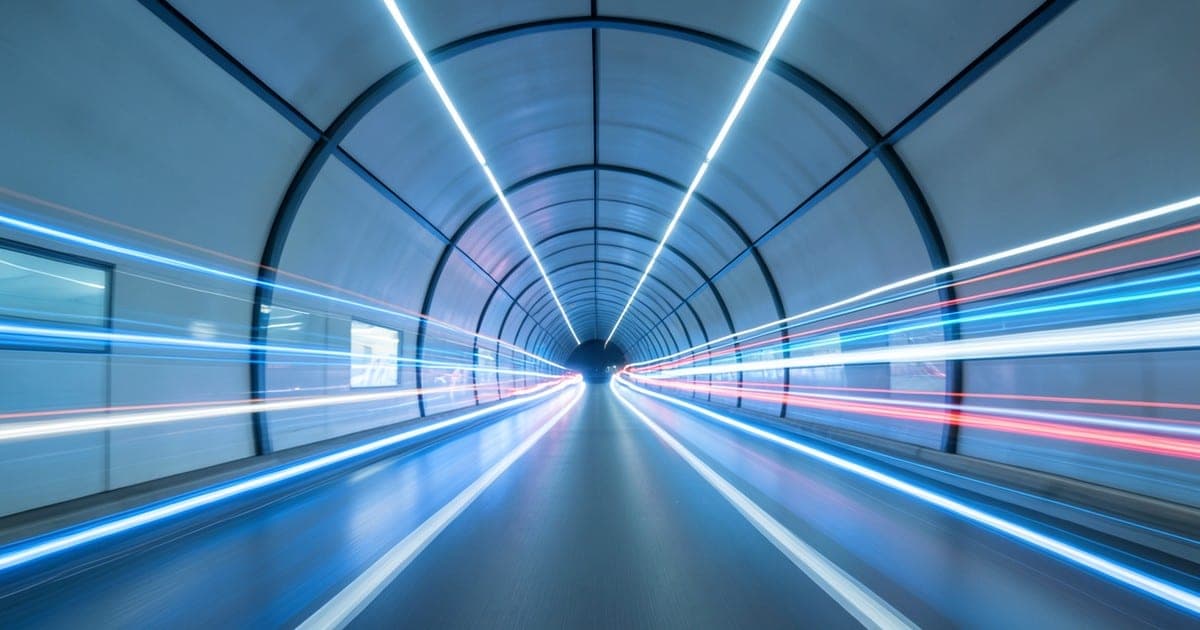 Long-exposure light trails racing through a tunnel