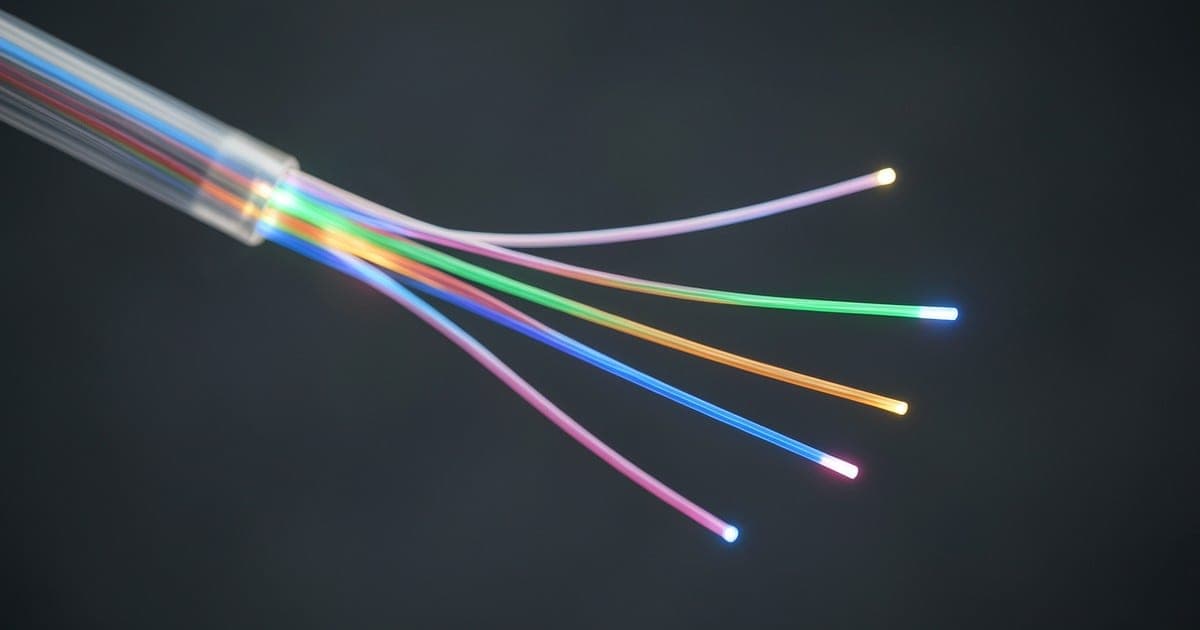 One fiber-optic cable fanning out into five glowing colored strands on a dark background